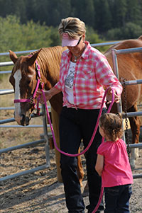Marcia Moore Harrison and her granddaughter, Elizabeth, leading their horse Jesse from the pasture